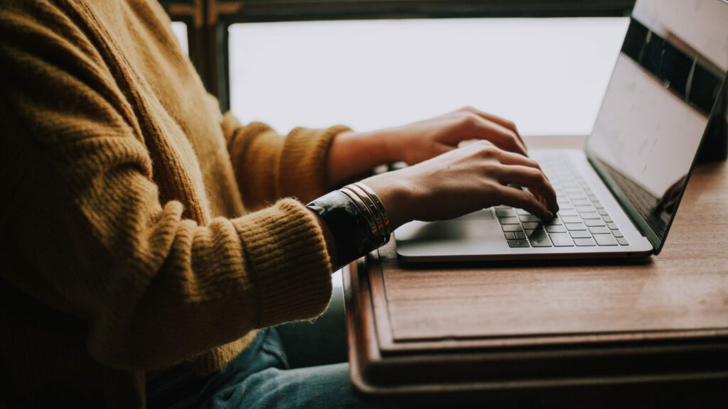 a person sitting at a desk typing on a laptop