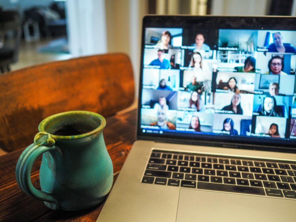A ceramic mug on a desk next to a laptop open to a group Zoom call